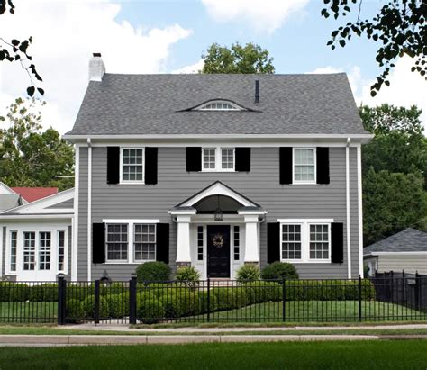 white house with grey metal.roof and.wood shutters|dark gray house with shutters.